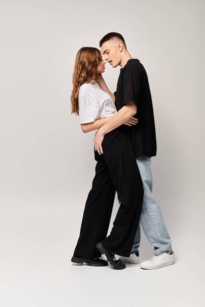Чоловік і жінка, закохана молода пара, стоїть поруч у студії з сірим фоном. - Фото, зображення