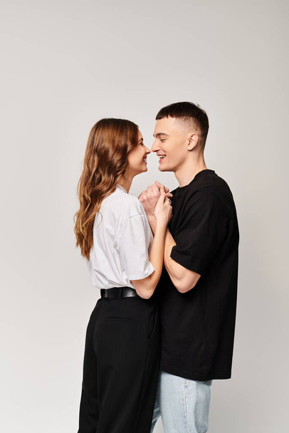 Ένα ερωτευμένο ζευγάρι, να στέκεται δίπλα-δίπλα σε ένα στούντιο με γκρίζο φόντο.. - Φωτογραφία, εικόνα