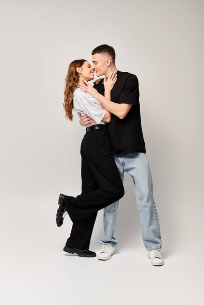 Ein Mann und eine Frau, ein junges Paar, tanzen zusammen in einem Studio vor grauem Hintergrund und zeigen Liebe und Harmonie. - Foto, Bild
