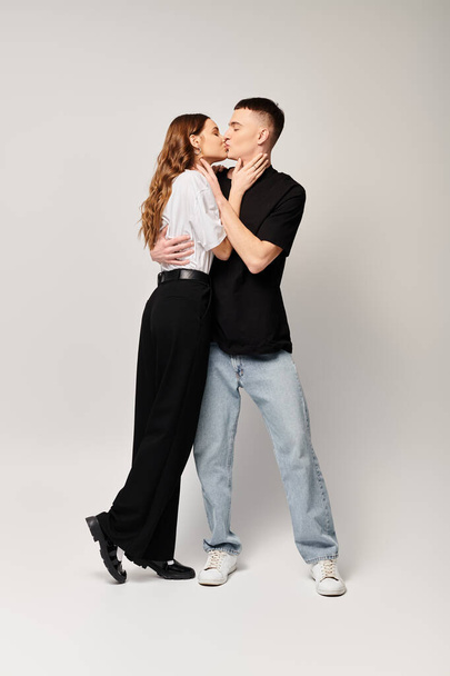 Um jovem casal, profundamente apaixonado, está lado a lado em um estúdio com um fundo cinza. - Foto, Imagem