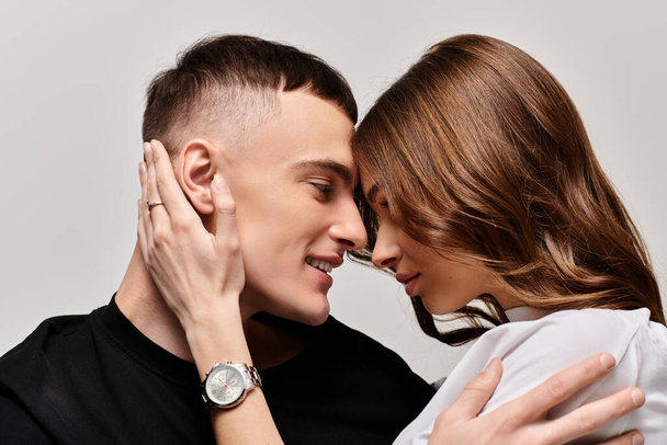 Ένας νεαρός άνδρας και μια γυναίκα αγκαλιάζονται τρυφερά σε ένα στούντιο με γκρι φόντο.. - Φωτογραφία, εικόνα