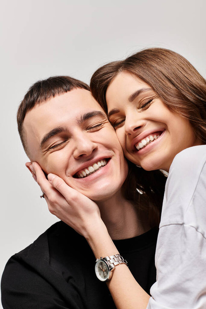 Un hombre y una mujer compartiendo un abrazo sincero, mostrando amor y afecto en un ambiente de estudio con un fondo gris. - Foto, imagen