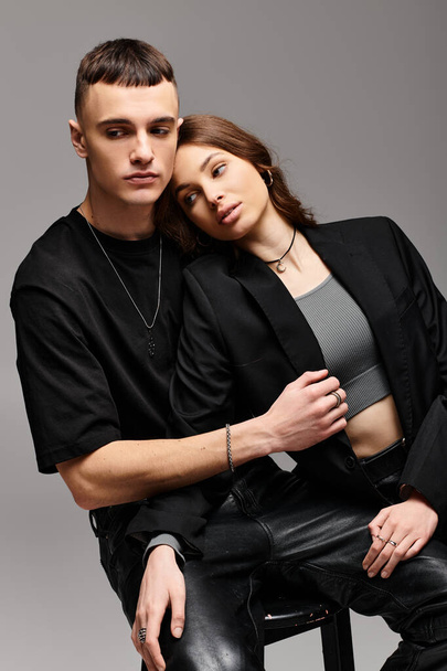Een man en een vrouw, een jong verliefd stel, zitten naast elkaar in een studio met een grijze achtergrond. - Foto, afbeelding