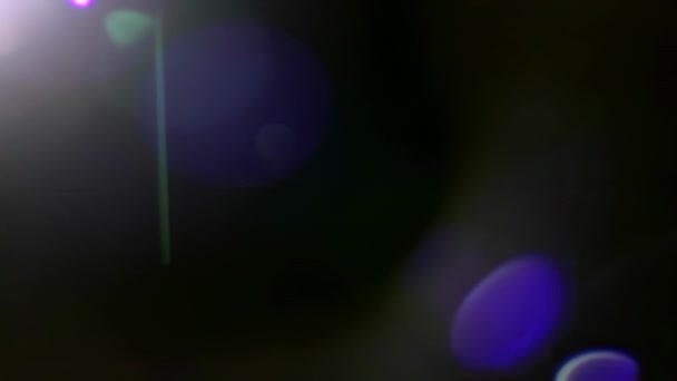 Настоящая утечка света, яркий луч, сияющий в объектив, создающий вспышку, фиолетовый боке и нимб, движущийся по верхней части рамки направо, на черном фоне для переходов и эффектов смешивания. - Кадры, видео