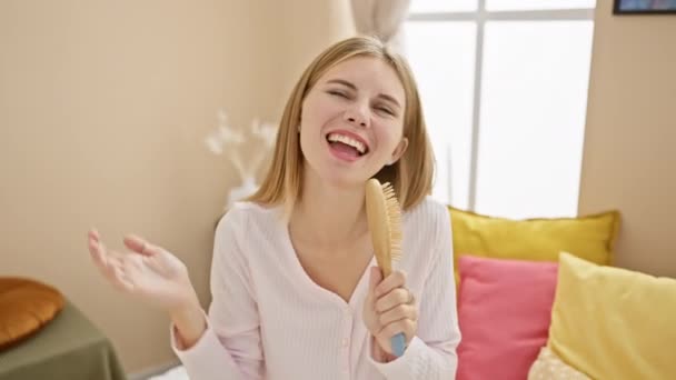 Een vrolijke jonge vrouw die thuis zingt met een haarborstel, die zorgeloos, mooi en lifestyle scènes oproept. - Video