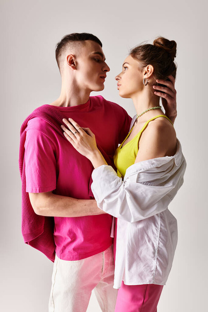 A stylish young couple in love, standing next to each other in a studio with a grey background. - Fotografie, Obrázek