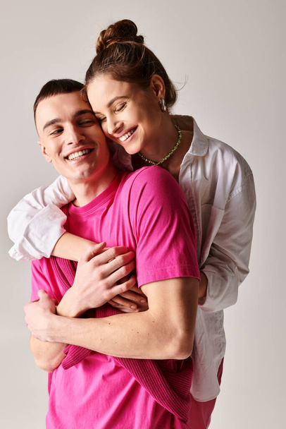 Ένα κομψό νεαρό ερωτευμένο ζευγάρι αγκαλιάζει παθιασμένα ο ένας τον άλλον σε ένα στούντιο, με γκρι φόντο. - Φωτογραφία, εικόνα