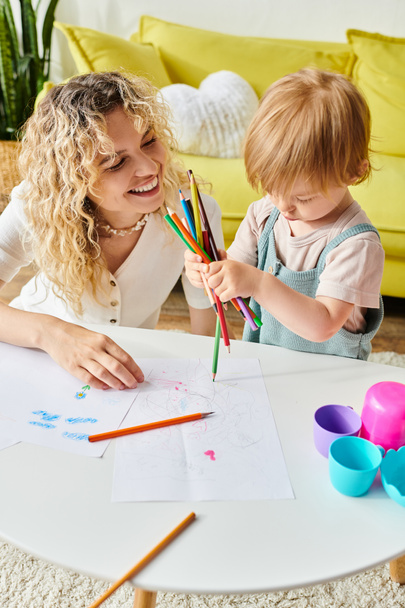 A curly mother and her toddler daughter bonding over crayons using the Montessori method of education at home. - Photo, Image
