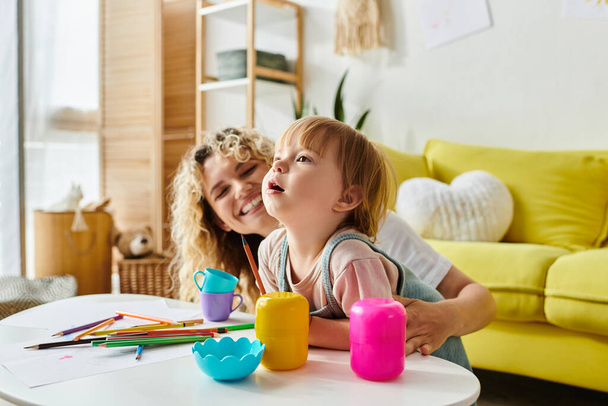 A curly-haired mother and her toddler daughter happily playing with toys in their cozy living room. - Photo, Image