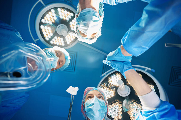 Медицинские работники и ассистенты, выполняющие операционную профессиональную помощь в операционной - Фото, изображение