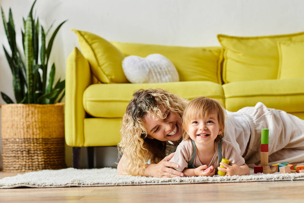 Uma mulher e uma criança com cabelo encaracolado se envolvem na educação Montessori juntos no chão, promovendo um vínculo carinhoso. - Foto, Imagem