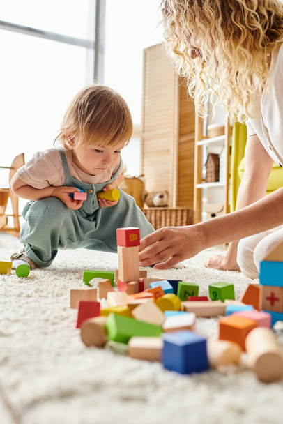 Uma mãe encaracolada e sua filha se envolvem em brincadeiras educativas usando o método Montessori no chão. - Foto, Imagem