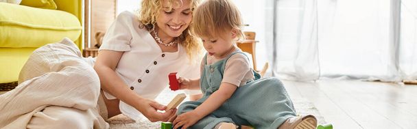 Kędzierzawa matka i jej córeczka bawią się zabawkami Montessori na podłodze, budując silną więź. - Zdjęcie, obraz