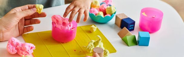 mother observes as her toddler daughter intricately molds and shapes colorful play dough on a table. - Photo, Image