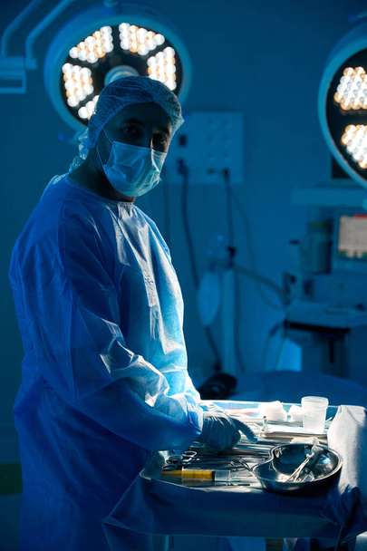 Chirurg męski z sterylnymi instrumentami przygotowujący się do operacji w nowoczesnym centrum medycznym - Zdjęcie, obraz