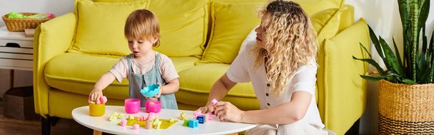 La madre riccia e la figlia minore si impegnano nell'educazione Montessori giocando con i blocchi su un tavolo.. - Foto, immagini
