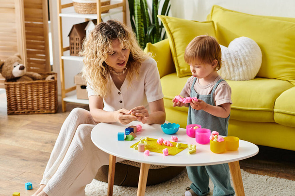 krullende moeder en peuter dochter gelukkig spelen met speelgoed, het beoefenen van Montessori onderwijs thuis. - Foto, afbeelding