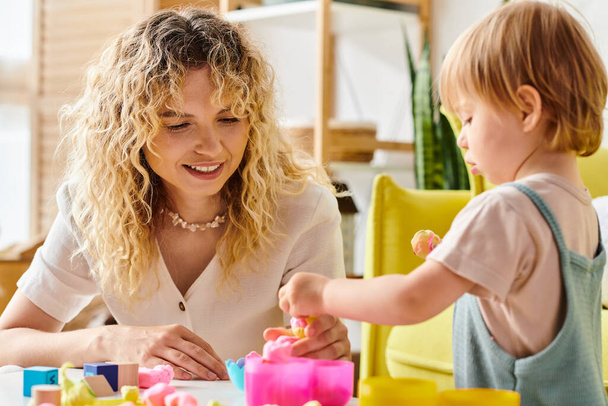 Uma mãe encaracolada e sua filha criança brincam alegremente com brinquedos Montessori em casa. - Foto, Imagem