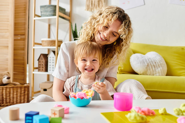 A curly mother and her toddler daughter engage in Montessori learning at a cozy table, exploring new discoveries. - Photo, Image