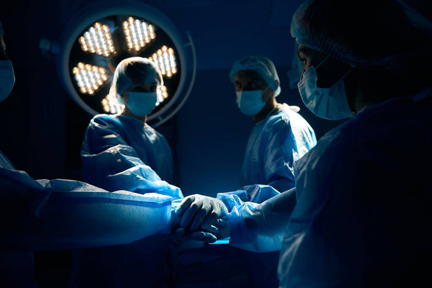 Ταλαντούχοι γιατροί που κρατιούνται χέρι-χέρι πριν την εγχείρηση στην κλινική - Φωτογραφία, εικόνα
