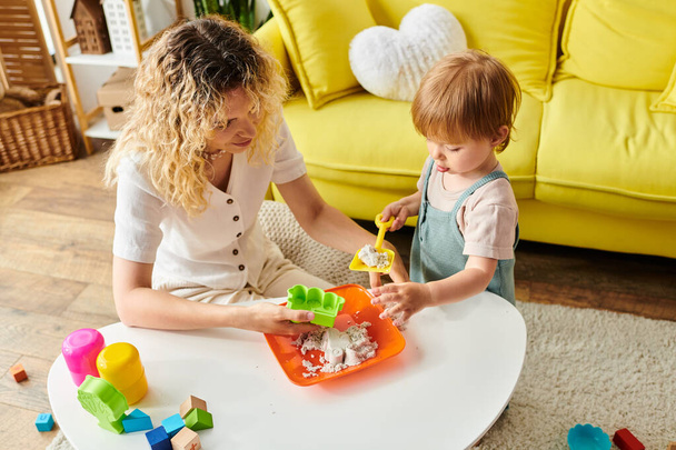 Eine lockige Mutter und ihre kleine Tochter beschäftigen sich mit der Montessori-Methode und spielen zu Hause mit Spielzeug. - Foto, Bild