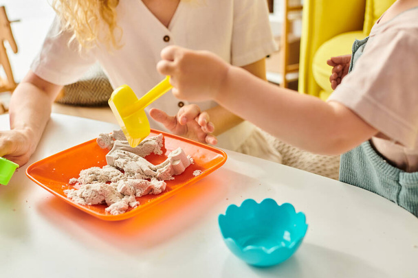 Un niño pequeño disfruta de una comida en una mesa guiada por su madre, utilizando el método Montessori de educación. - Foto, Imagen