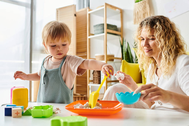 La madre rizada y su hija pequeña exploran juntos los juguetes Montessori, fomentando la creatividad y el aprendizaje en casa. - Foto, imagen
