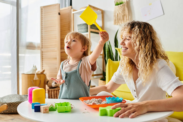 Une mère bouclée et sa fille en bas âge profitant d'un temps de jeu de qualité en utilisant la méthode Montessori d'éducation à la maison. - Photo, image