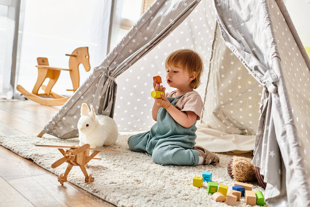 Un bambino piccolo immerso in un gioco di giocattoli all'interno di una vibrante tenda da gioco, con il metodo Montessori. - Foto, immagini