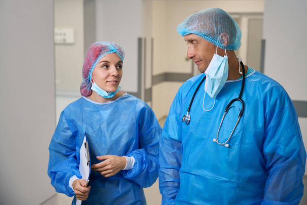 Врачи-хирурги после операции говорят в больничном коридоре - Фото, изображение