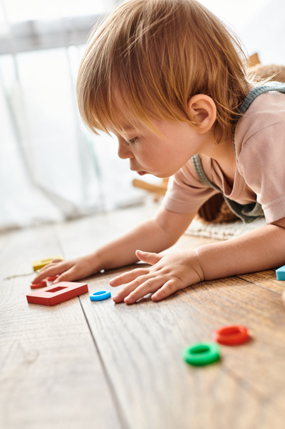 Un bambino piccolo assorto a giocare con i giocattoli sul pavimento, esplorare la creatività e l'apprendimento. - Foto, immagini