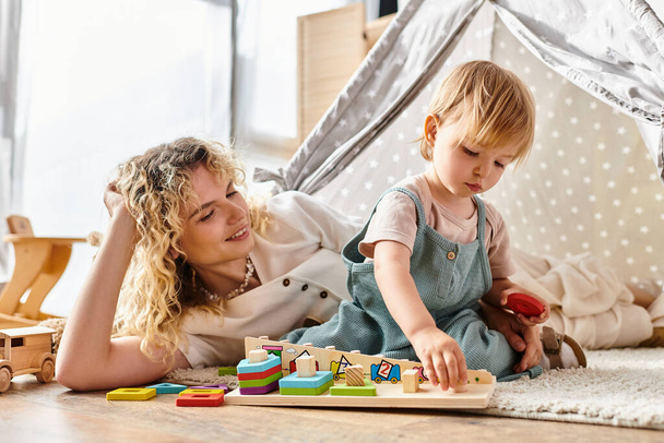 Uma mãe de cabelos encaracolados e sua filha criança estão brincando alegremente com brinquedos educativos usando o método Montessori em casa.. - Foto, Imagem