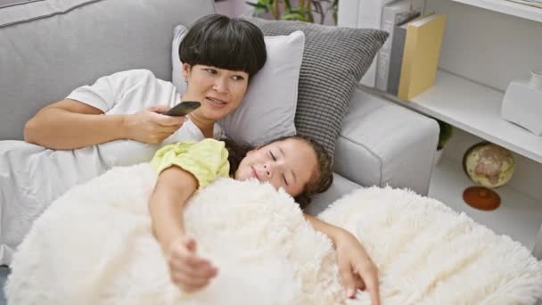Filmnacht-Zauber, fröhliche Mutter und Tochter, die Spaß am Fernsehen haben, zu Hause auf dem bequemen Sofa liegen, ihr glückliches Lächeln erhellt den Raum - Filmmaterial, Video