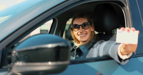 mulher feliz mostrando sua nova carteira de motorista fora da janela do carro e dirigindo para longe - Filmagem, Vídeo