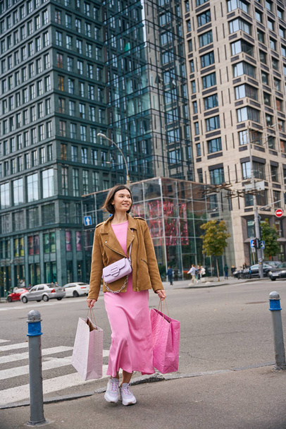 Allegro donna sorridente che cammina con borse della spesa di carta comprare vestiti nei negozi sulla strada della città - Foto, immagini