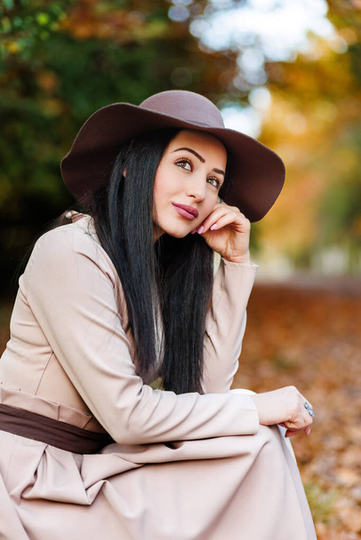 Прийняття сезону. Молода жінка в стильному вбранні сидить у парку і знаходить гармонію з осіннім середовищем - Фото, зображення