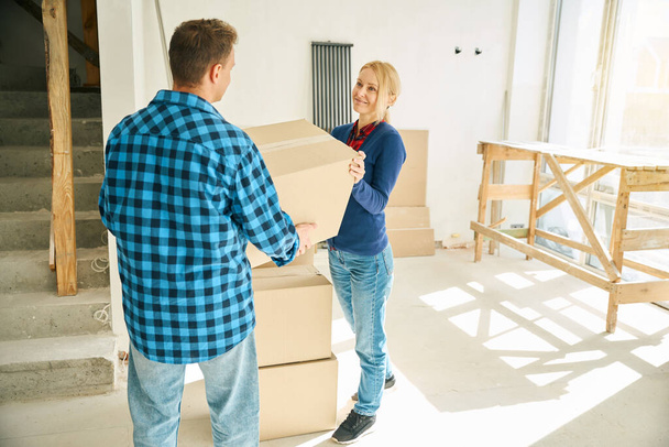 Couple adulte heureux debout dans la chambre et mettre des boîtes en carton dans l'ordre après avoir déménagé dans une nouvelle maison - Photo, image