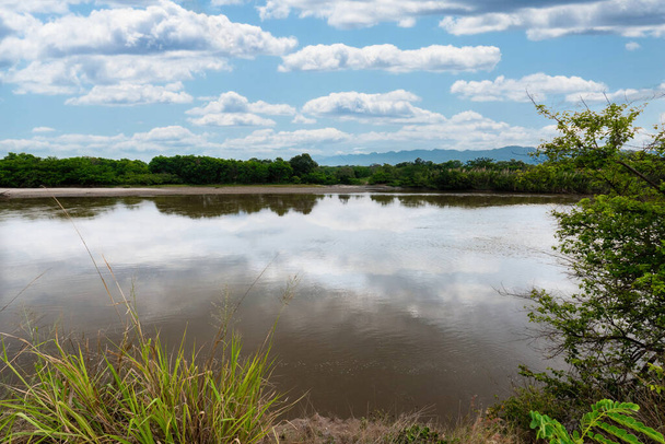 Neiva, Huila, Kolumbia. Maj 2019: Panoramiczny krajobraz z niebieską łodzią na brzegu rzeki Magdaleny. - Zdjęcie, obraz