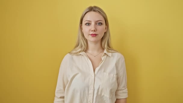 Verbazingwekkende jonge blonde vrouw vrolijk wijzen, kijken verrast op geïsoleerde gele achtergrond, uiten vrolijk vertrouwen - Video
