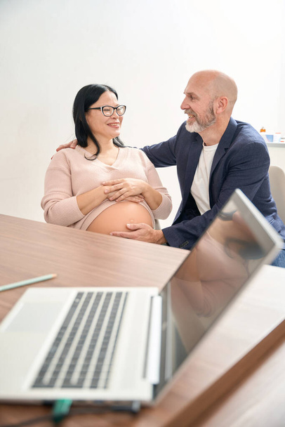Uiterst gelukkig volwassen paar bezoeken gynaecoloog kantoor en oprecht blij horen nieuws dat de baby ontwikkelen volgens termen van zwangerschap, reproductologie kliniek - Foto, afbeelding