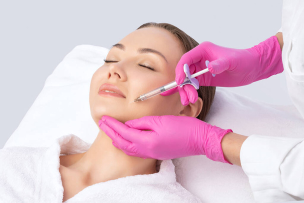 El cosmetólogo hace rejuvenecedoras inyecciones antiarrugas en la cara de una mujer hermosa. Cosmetología estética femenina en un salón de belleza. - Foto, imagen