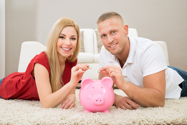 Couple Inserting Coin In Piggybank - Photo, image