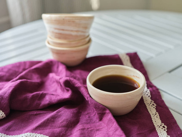 Weibliche Hand auf dem weißen Tisch mit einer keramischen Tasse Kaffee. Rest-Relax-Konzept. Alte Dorfstimmung. Aus nächster Nähe. Hochwertiges Foto - Foto, Bild