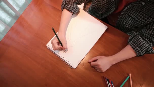 Overhead view of a person sketching on a white pad with a pencil, creativity and art concept, with copy space during the daylight - Metraje, vídeo
