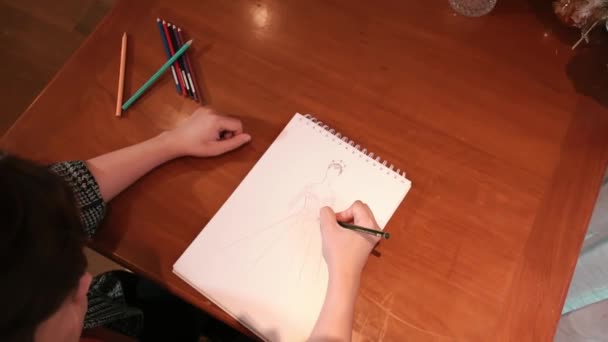Primo piano dello schizzo delle mani con matita su carta, processo creativo di disegno, sfondo del tavolo in legno durante il giorno - Filmati, video