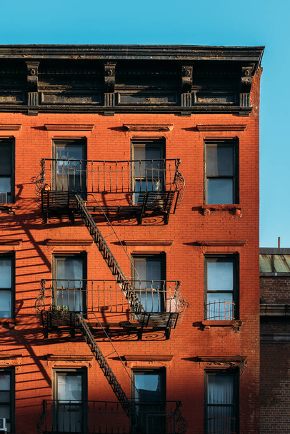 Теплый свет украшает классический пожарный выход на кирпичном здании Нью-Йорка. - Фото, изображение