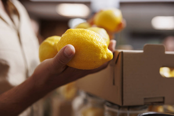 Homme achetant des citrons cultivés par zéro déchet propriétaire de supermarché dans son jardin, fermer. Client heureux de trouver des pesticides écologiques fruits frais gratuits dans le magasin local, fond flou - Photo, image