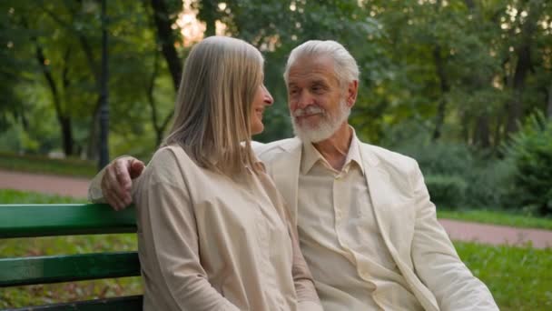 Прекрасна старша літня щаслива кавказька пара жінка чоловік приймає калюжу романтичне побачення під час флірту на пенсії, святкуючи річницю сім'ї за межами лавки міського парку. Бондаж шлюбні відносини любов - Кадри, відео