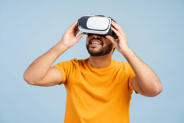 Profi afro-amerikai játékos visel VR szemüveg videojáték, elszigetelt kék alapon. Innovatív koncepció, 3D szimuláció  - Fotó, kép