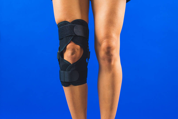 primo piano colpo di una gamba con ginocchiera supporto su uno sfondo blu, concetto di recupero. Foto di alta qualità - Foto, immagini
